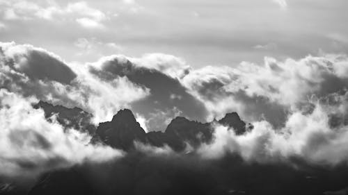 Grayscale Photo of Mountains Under Cloudy Sky