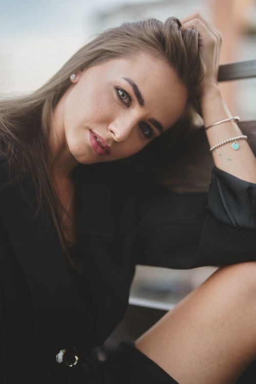 Free Beautiful young woman in black clothing posing outdoors with a thoughtful expression. Fashion and elegance captured. Stock Photo