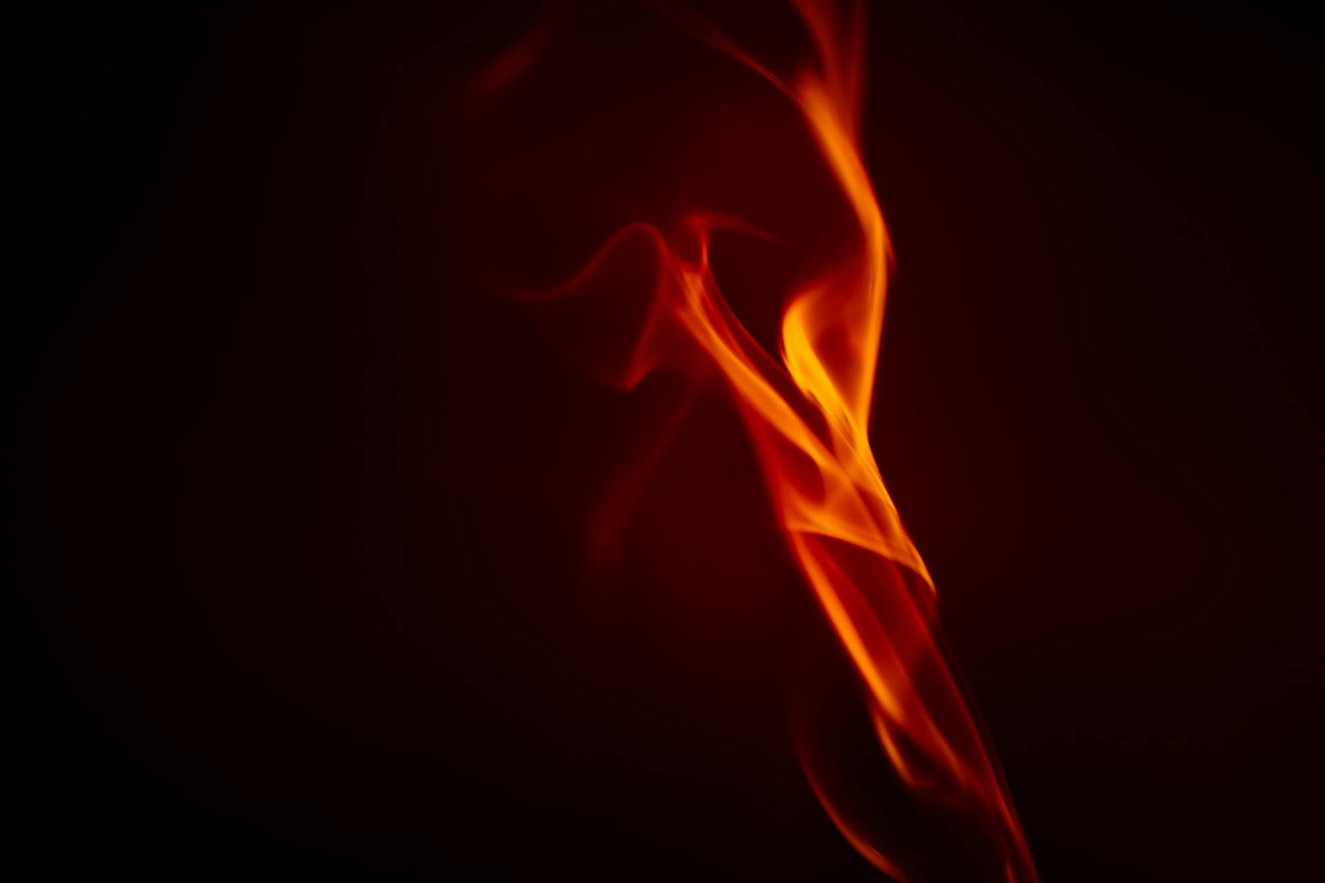 A vivid close-up image capturing the dynamic movement of a fire flame against a dark background.