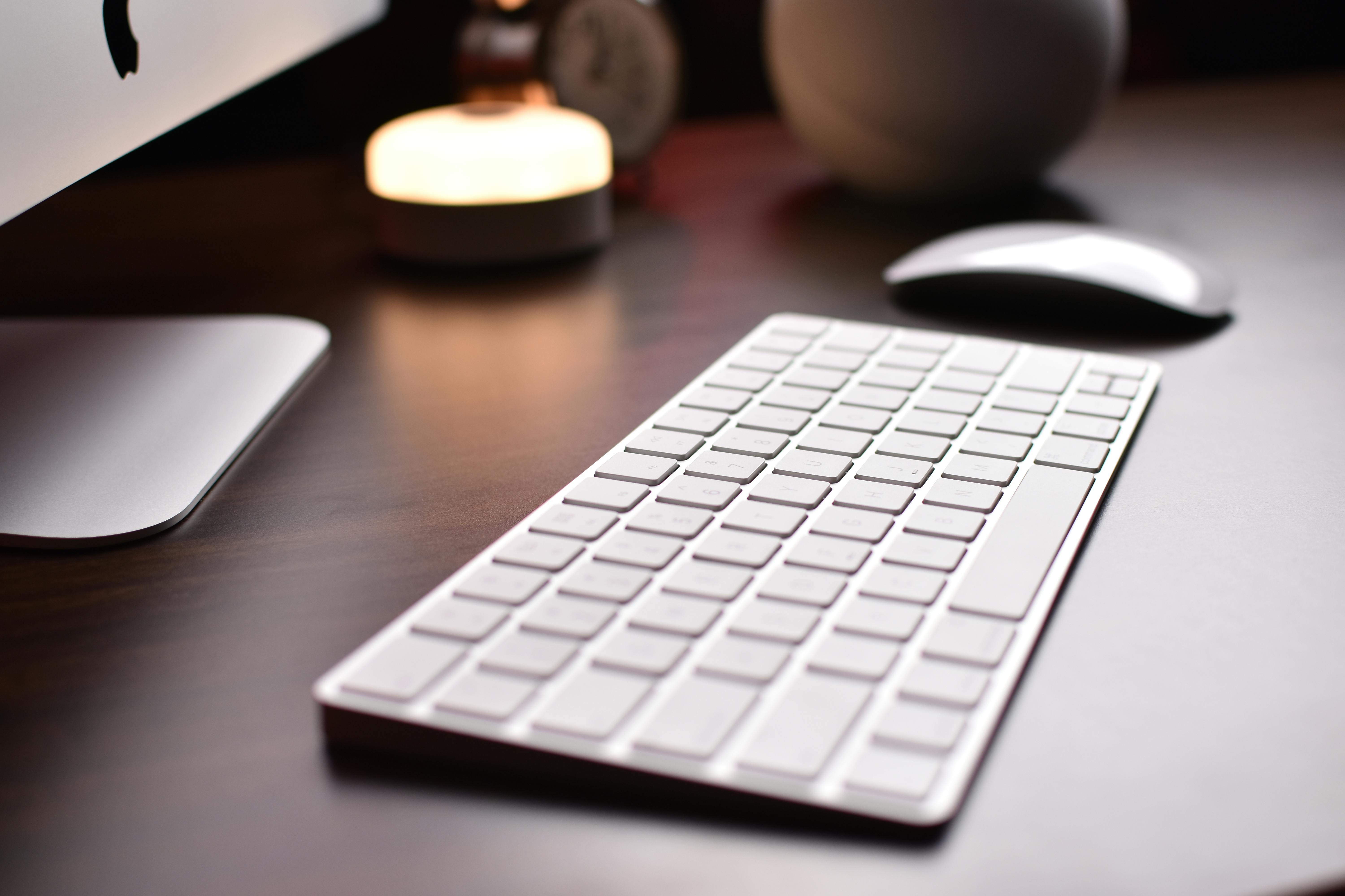 Close-up of a wireless keyboard with mouse on a wooden table, creating a modern workspace.