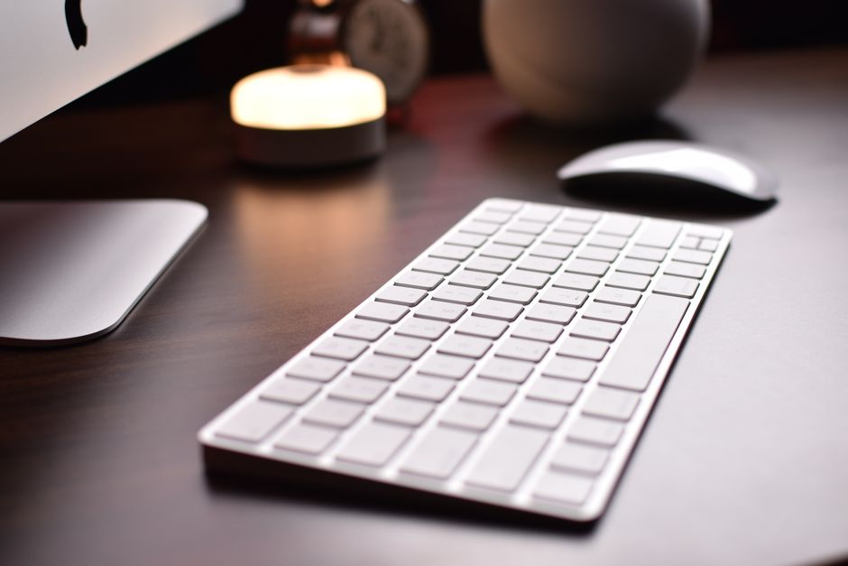 Close-up of a wireless keyboard with mouse on a wooden table, creating a modern workspace.