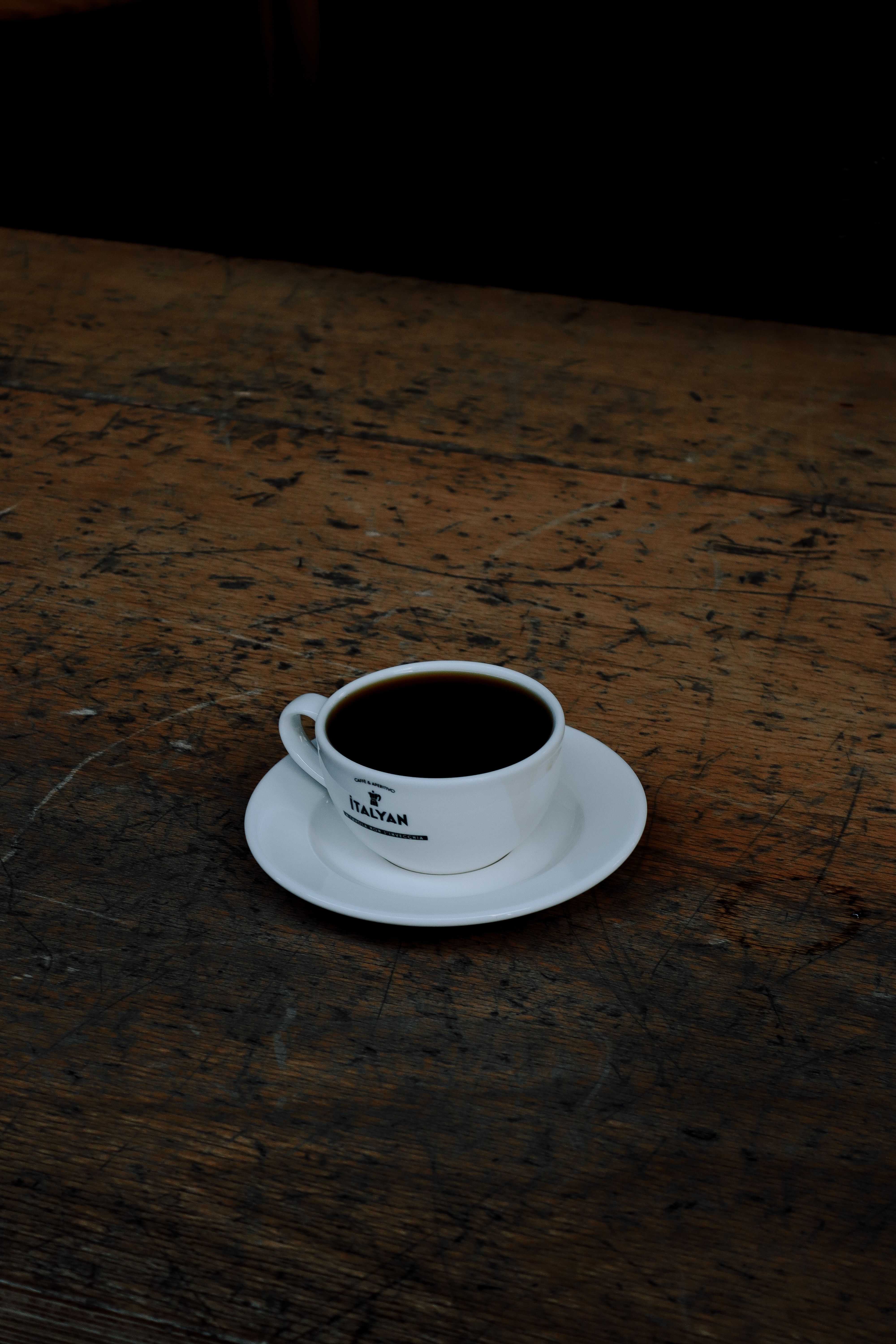 A ceramic cup of coffee rests on a rustic wooden table, offering a cozy and inviting scene.