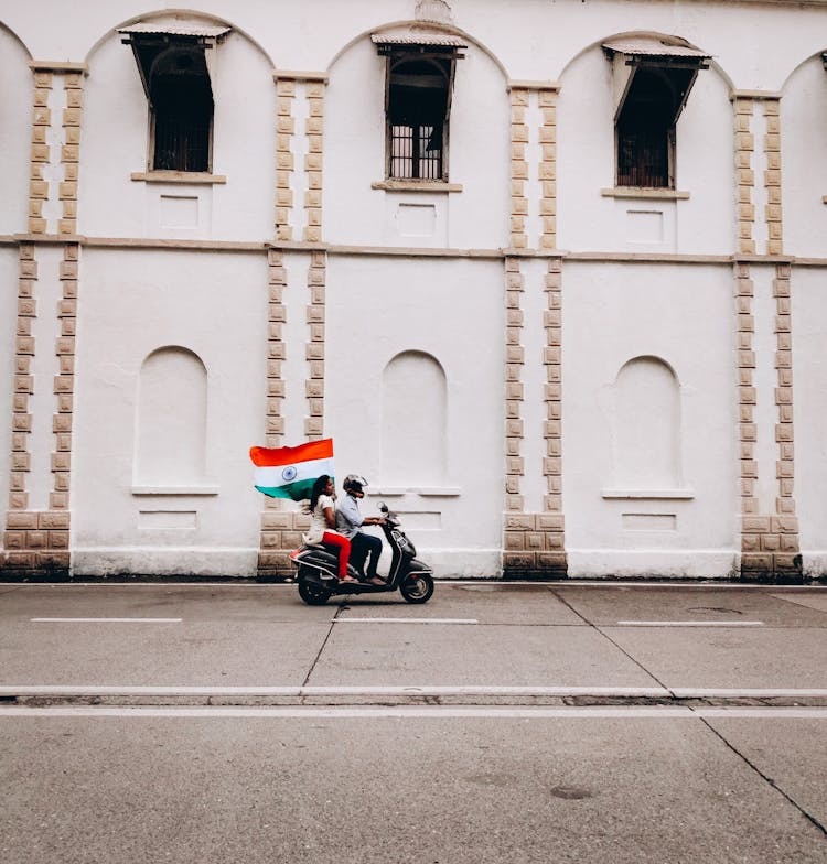 Man And Woman Riding On A Motorbike Holding A Flag Of India