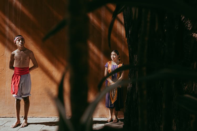 Boy And Girl Standing Under Wall In Shade