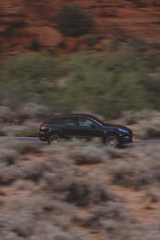 Black SUV speeds along a desert road with blurred motion for a dynamic outdoor scene.