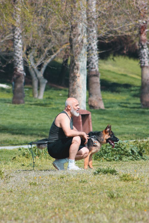 Man Sitting with a German Shepherd Dog on a Grass on Park