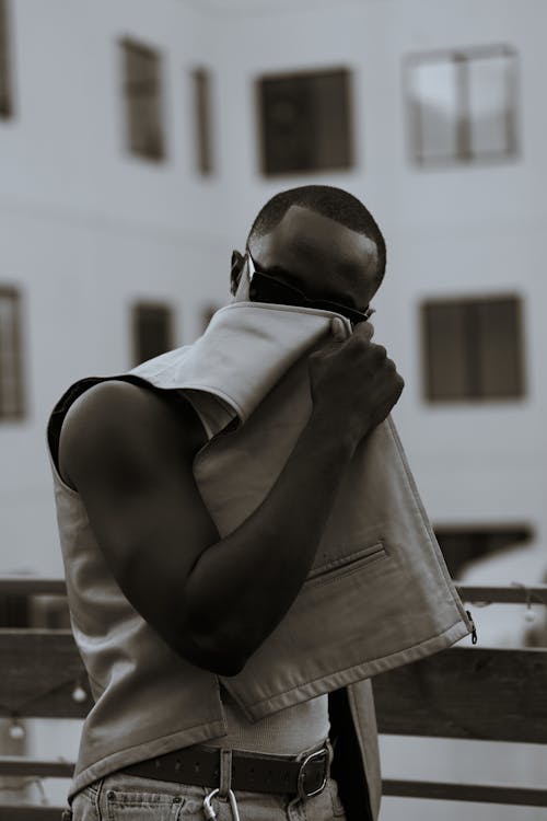 Young Man Posing in a Leather Vest Covering His Face