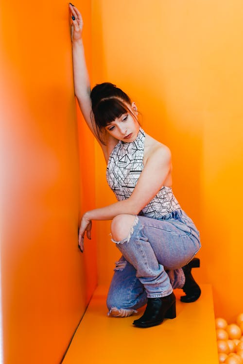 Woman in Stylish Clothes Posing in Orange Studio
