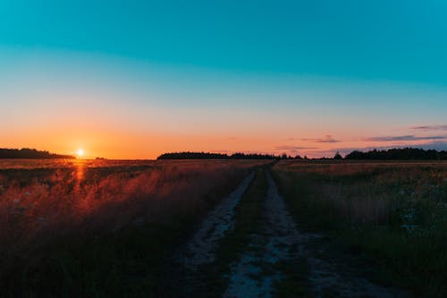 Безкоштовне стокове фото на тему «блакитне небо, ґрунтова дорога, Захід сонця»