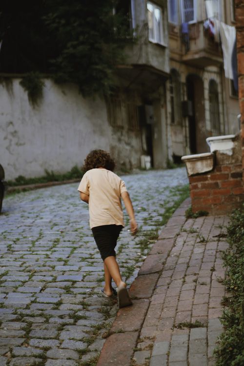 Free A young child walks up a cobblestone street in Istanbul, capturing a candid street scene. Stock Photo
