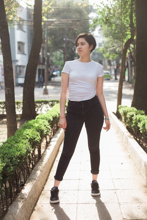 Woman in White Shirt Standing on a Walkway