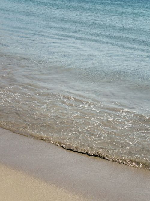 Free Peaceful waves gently lap the sandy shore in Antiparos, Greece. Stock Photo