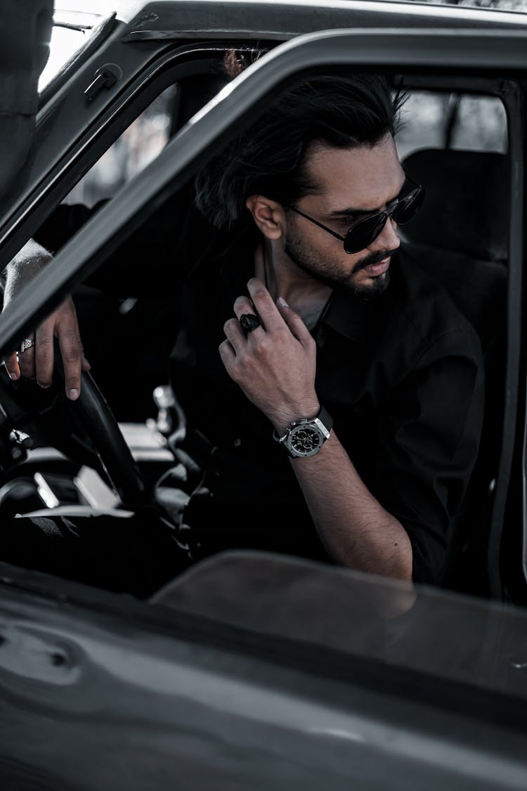 Man In Black Shirt Wearing Sunglasses Sitting Inside A Car