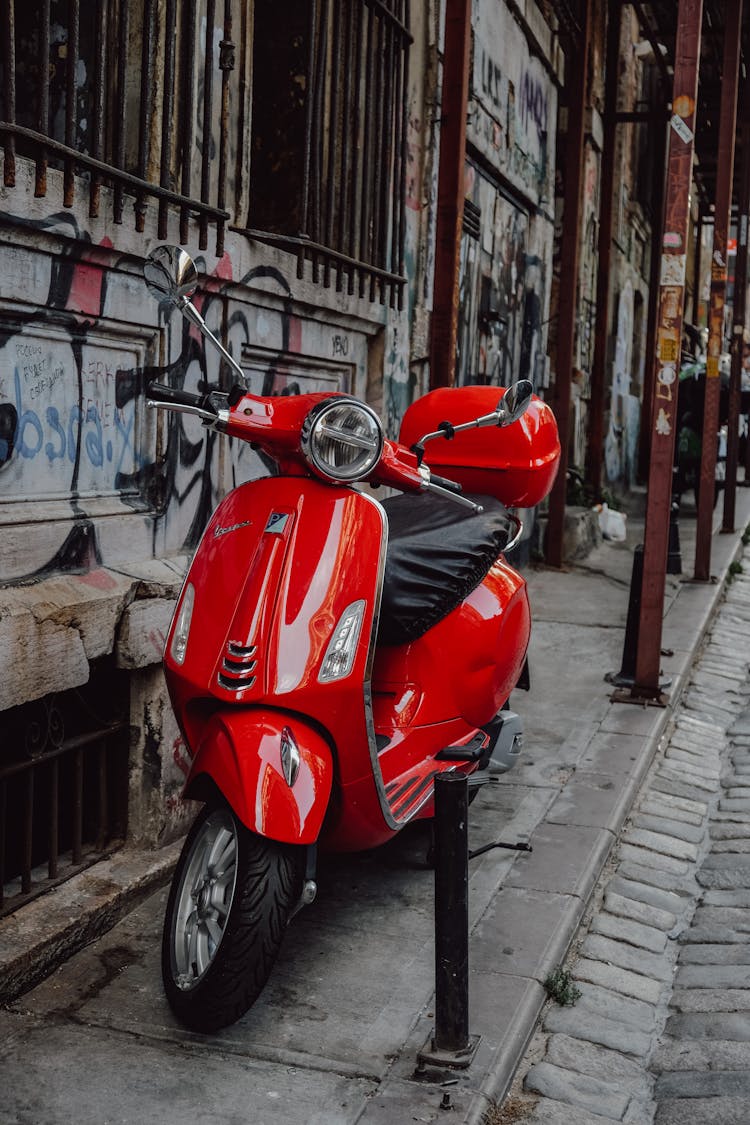 Red Motor Scooter Parked Beside Wall With Graffiti