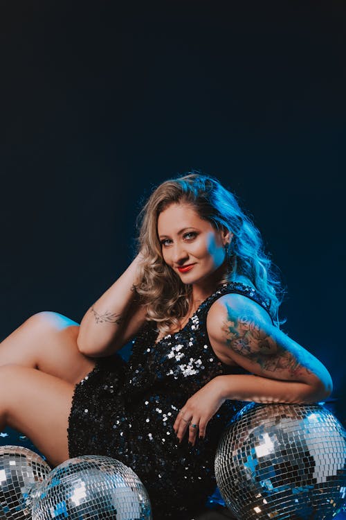Woman in a Black Sequin Dress Posing Leaning on Disco Balls