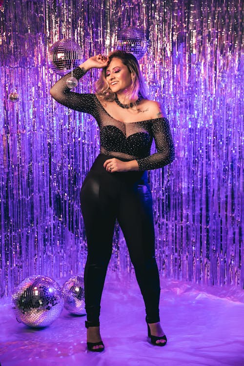 Young Woman in a Party Outfit Posing on the Background of Tinsel and Disco Balls 