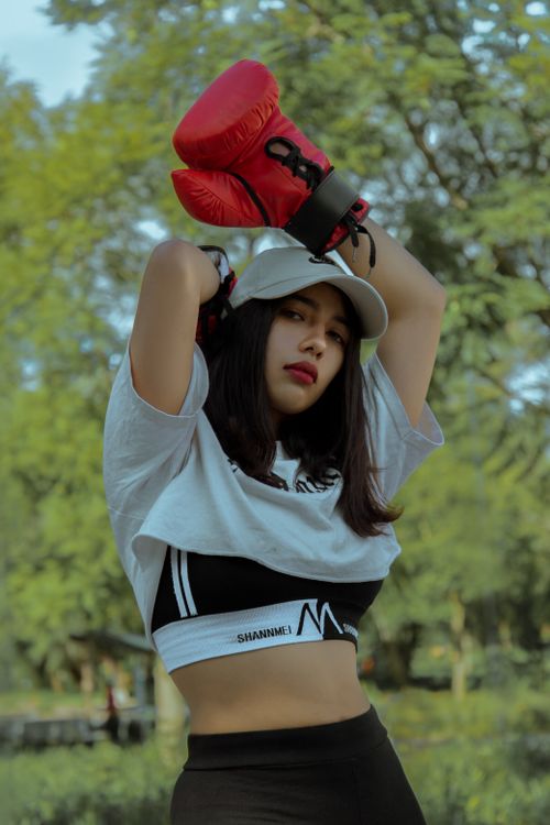 Free Confident young woman wearing boxing gloves and sportswear in a natural outdoor setting. Stock Photo
