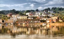 迷人的沿海小镇里，色彩缤纷的房屋倒映在平静的水中，映衬着晴朗的天空