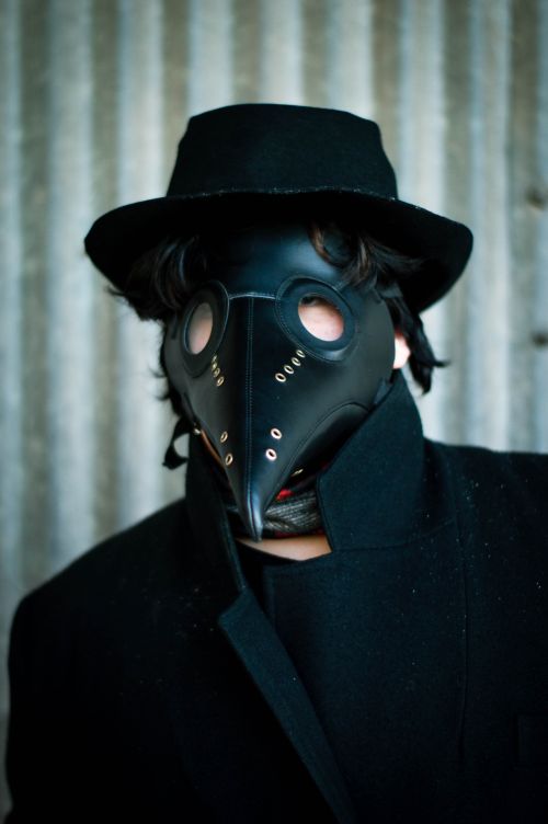 Free A mysterious figure in a black plague doctor mask and coat, evoking a gothic, eerie atmosphere. Stock Photo