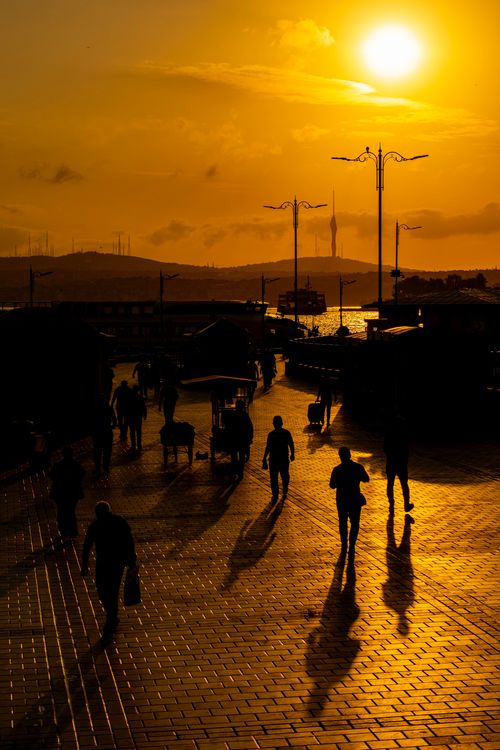 Free People walking on a city street at sunset creating dramatic silhouettes with a golden sky. Stock Photo