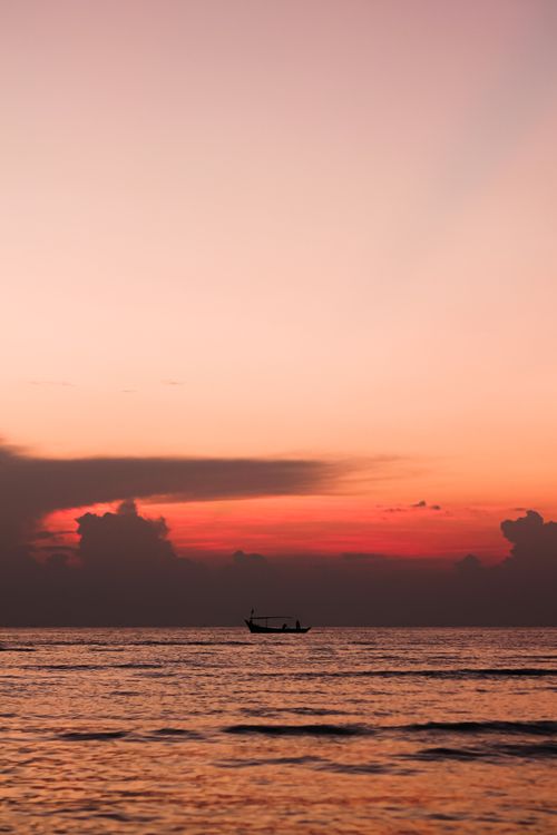 Free Peaceful sunset in Cirebon, Indonesia with boat silhouettes against a pink sky. Stock Photo