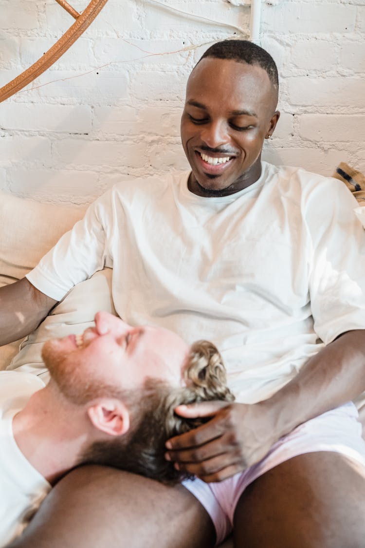 Man Holding His Head On His Boyfriend Lap In Bed 