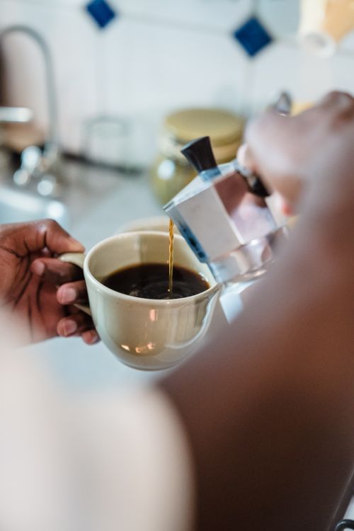 Free Warm coffee being poured into a cup in a home kitchen setting, embodying comfort and freshness. Stock Photo