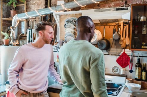 Free Two men cooking in a stylish, rustic kitchen, enjoying a shared moment. Stock Photo