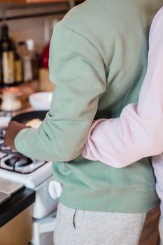 Couple embracing while cooking together in a cozy kitchen setting.