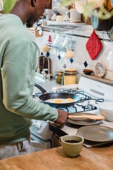A man prepares fried eggs in a home kitchen, showcasing a cozy morning routine.
