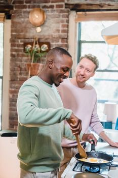 A cheerful couple cooking eggs together in a cozy kitchen, embodying love and partnership.