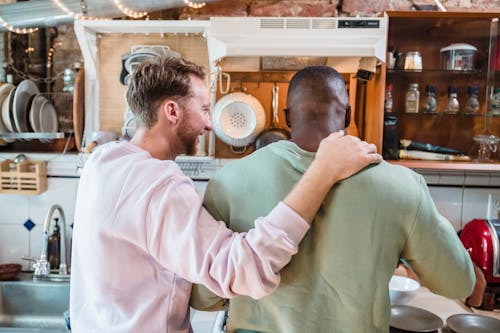 Man Holding Hand on Boyfriends Shoulder in a Kitchen 