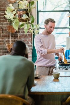 Two men cooking and enjoying a cozy meal in a stylish kitchen, showcasing warmth and companionship.
