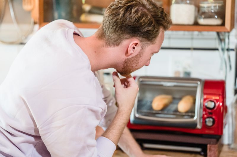 toaster oven on a break room counter with bread and bagels nearby