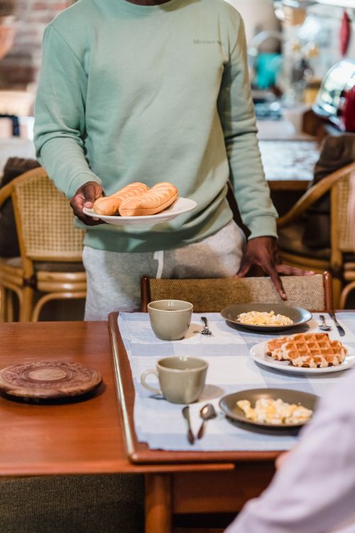 Free An inviting breakfast scene featuring croissants, waffles, and coffee served in a cozy kitchen setting. Stock Photo