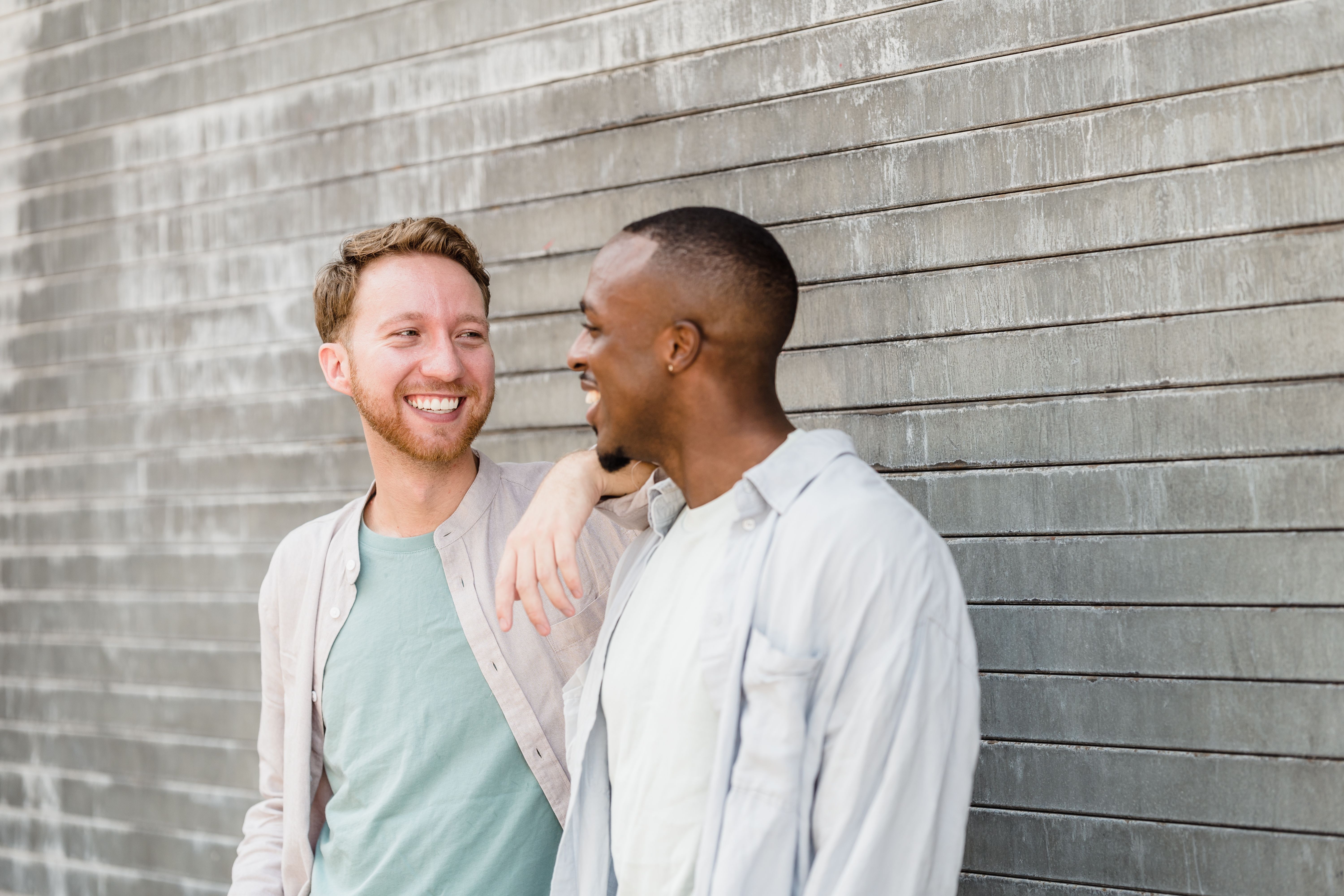 Portrait of Two Smiling Men Standing by the Wall · Free Stock Photo