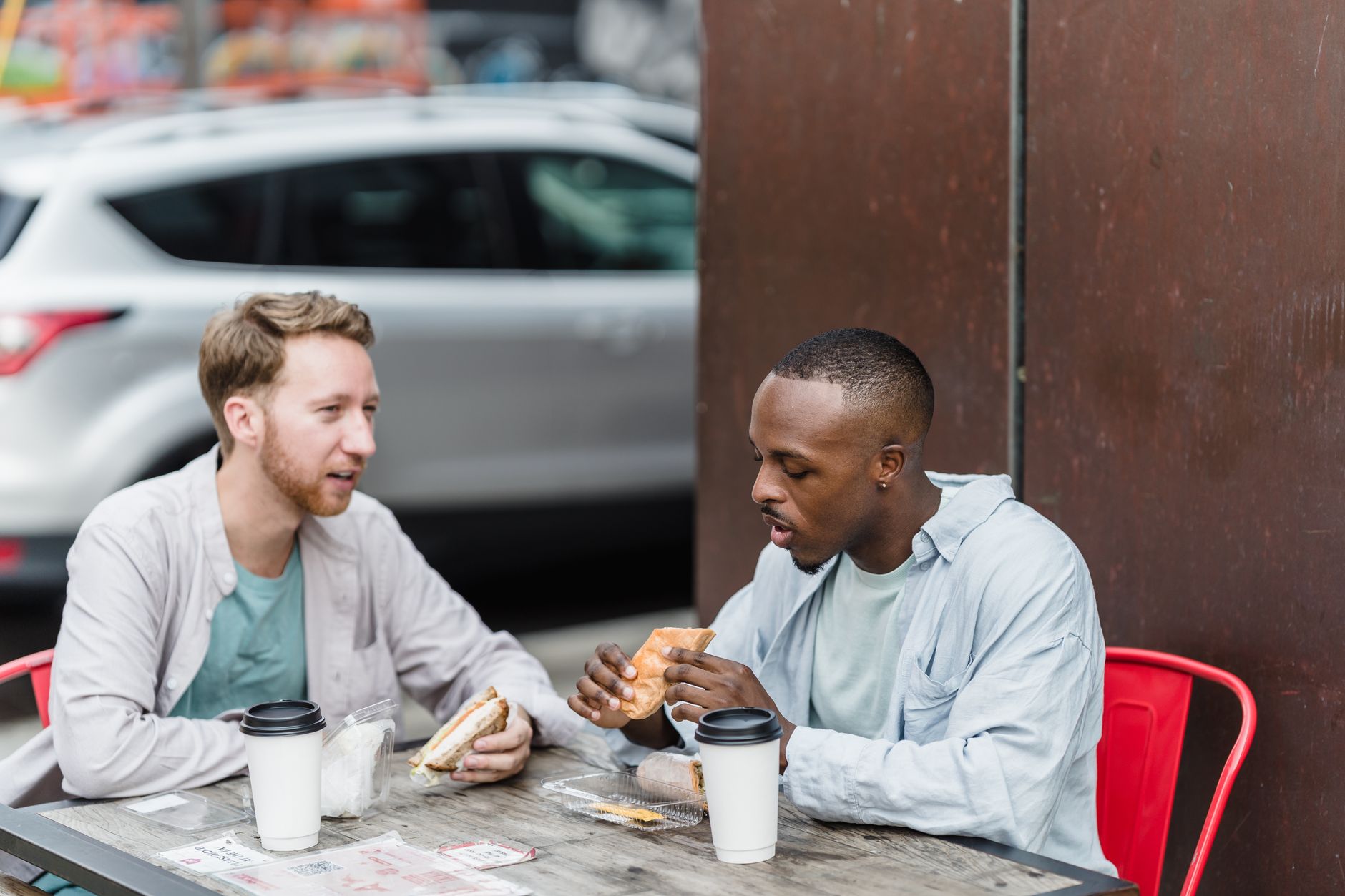 Two people comparing options on a tablet across a cafe table in daylight