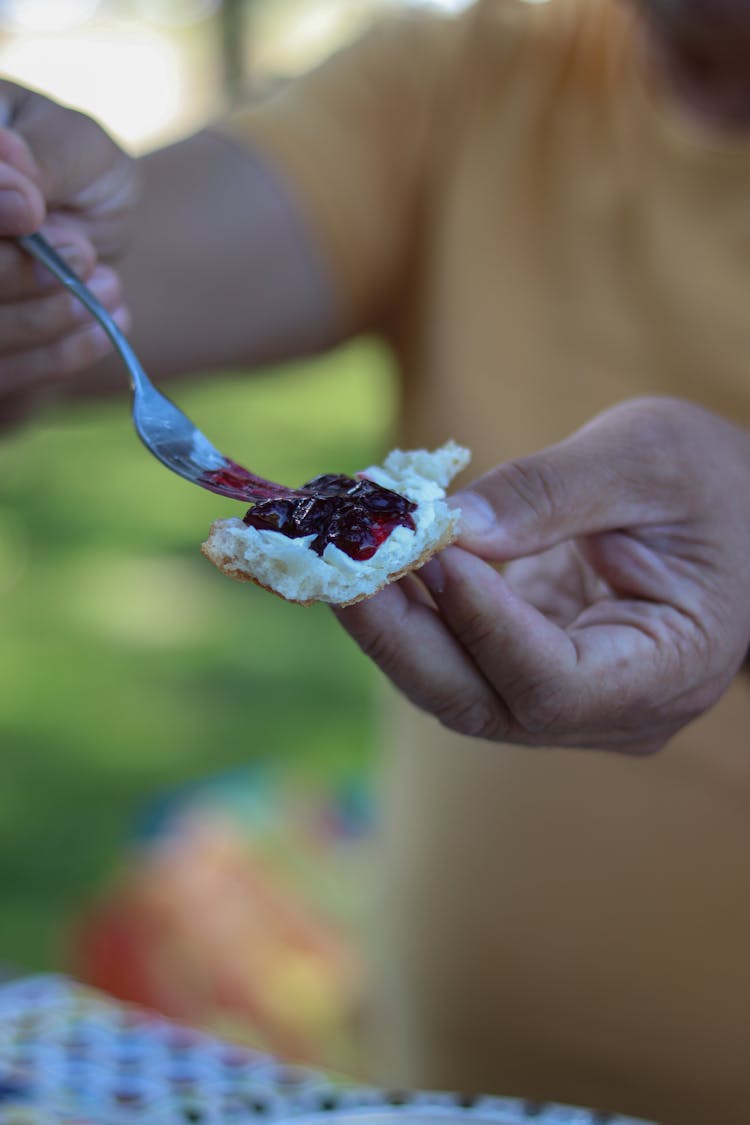 A Person Spreading Jam On The Bread