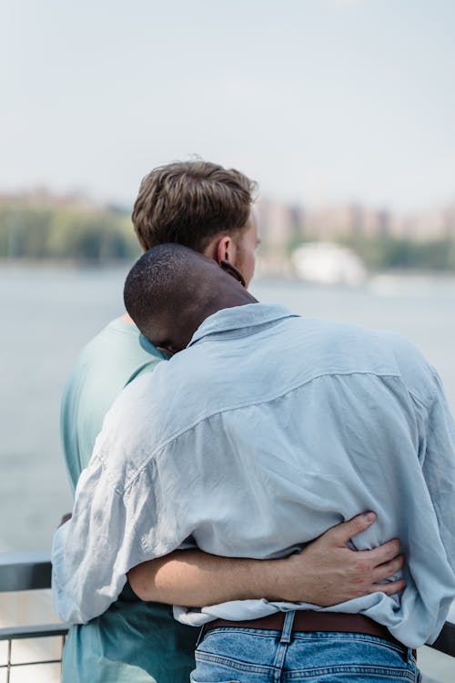 Men Standing and Hugging near Water