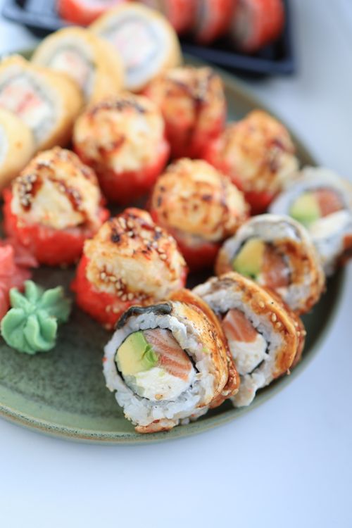 Free Colorful sushi rolls with various fillings on a green plate, perfect for a gourmet meal. Stock Photo