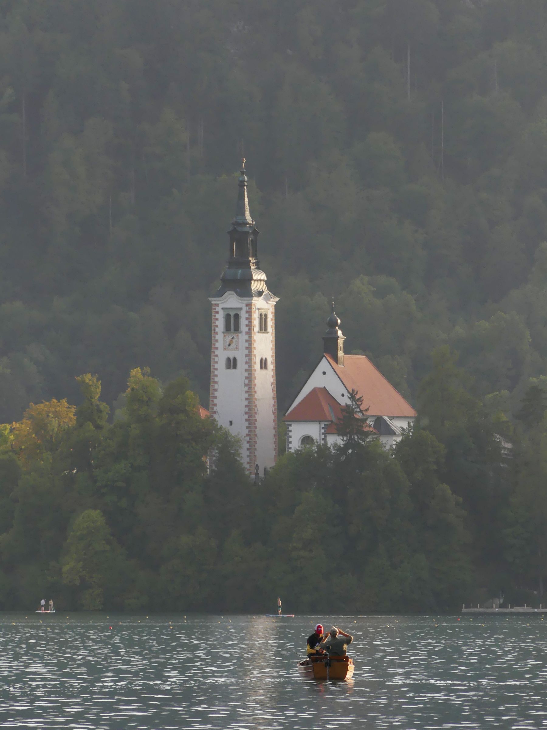 Church on Bled Island seen across the lake with a wooden boat