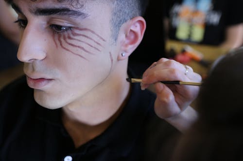 Close-up of Woman Painting a Young Mans Face 