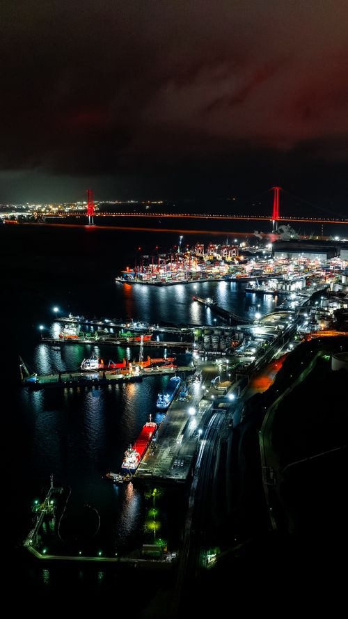 Free Aerial night view of a vibrant urban port with illuminated ships and city lights reflecting on water. Stock Photo