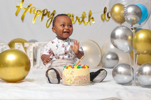 Free Adorable child enjoying a birthday party with a colorful cake. Perfect for festive occasions. Stock Photo