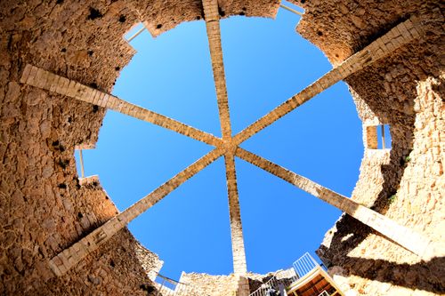 Free Low angle view of a circle-shaped stone structure with beams and clear blue sky. Stock Photo