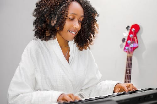 Gratis stockfoto met Afro-Amerikaanse vrouw, badjas, elektronisch toetsenbord
