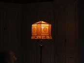 A classic vintage lamp with an intricate lampshade illuminates a dimly lit room, creating a nostalgic ambiance.