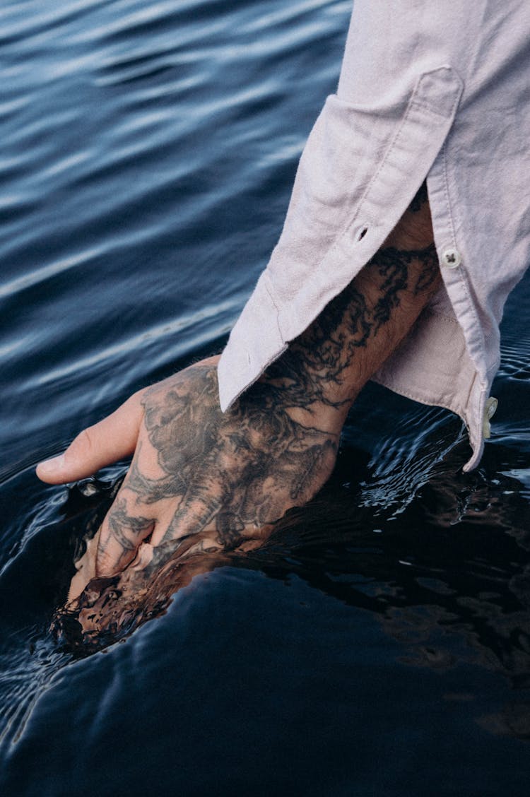 Tattooed Hand Touching Water Surface