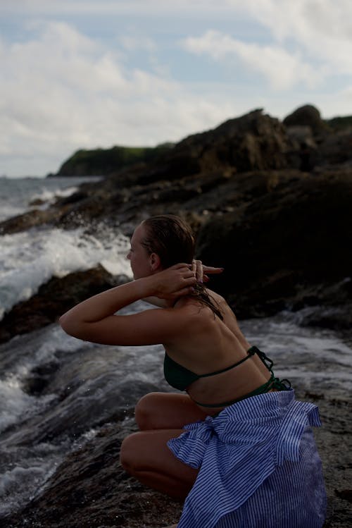 Woman Sitting on a Rocky Shore