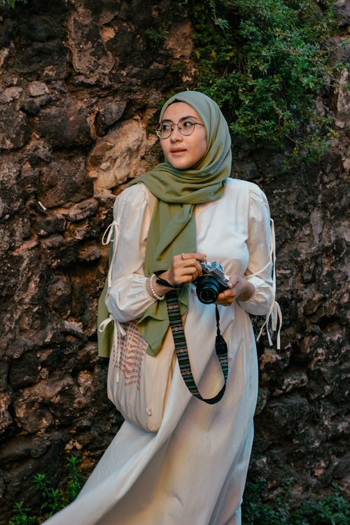 Free Woman in hijab holding a camera near a stone wall in İstanbul. Stock Photo